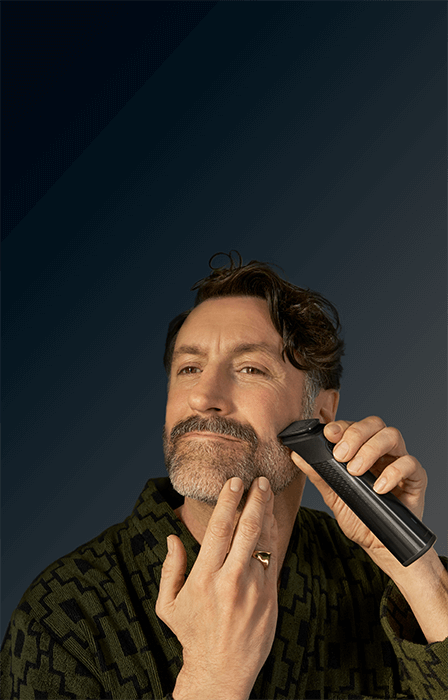 Mężczyzna trzyma w ręce urządzenie multigroom