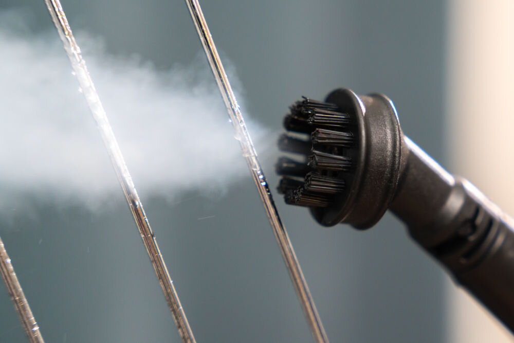 ODKURZACZ PIORĄCY SPOTCLEAN GOTZE&JENSEN CSC600 ze szczotką uniwersalną szeroką do butów do czyszczenia tapicerki meblowej samochodowej dywanów Bardzo bliskie ujęcie małej okrągłej szczotki parowej odkurzacza, z której wydobywa się para, czyszczącej metalowe pręty (np. grzejnika).