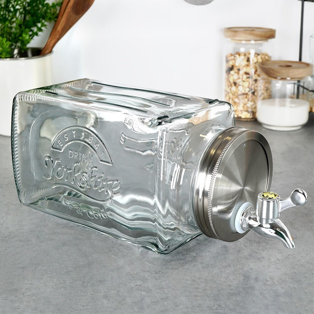 Szklany słój do napojów z kranikiem, o pojemności 3,5 litra, leży na blacie kuchennym. Na słoju widoczny jest napis: \'EST 1926 DRINK Yorkshire Ice Cold\'.