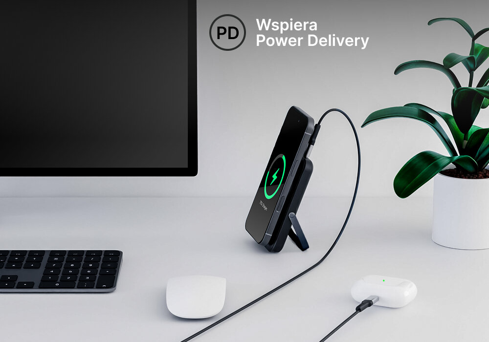 Powerbank QUALO QMPB5-LD-00 MagSafe 10000 mAh Czarny, Dziel się energią, Powerbank stoi na biurku a do niego podłączony smartfon po kablu