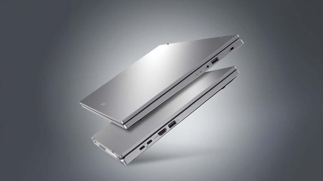 Dwa srebrne laptopy zamknięte, ułożone jeden nad drugim, z widocznymi portami po bokach. Na obudowie jednego z laptopów znajduje się logo producenta.