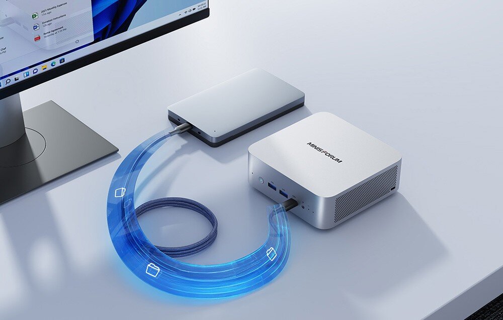 Komputer MINISFORUM M1 PRO-125H Mały komputer podłączony kablem do zewnętrznego dysku obok monitora