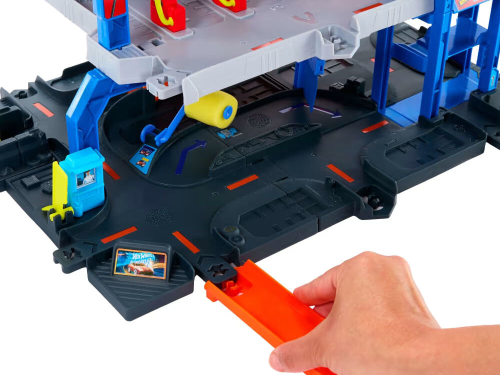 Tor Hot Wheels Mega Garaż Gigapętla + auto JBM74 Duży, zdalnie sterowany samochód-zabawka typu monster truck marki Hot Wheels, w kolorze pomarańczowym i czarnym, z grafiką imitującą pysk tygrysa lub rekina (Monster Shark). Ma cztery ogromne czarne opony z pomarańczowymi felgami. Tło jest białe.