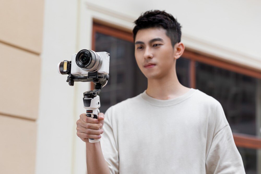 Gimbal ZHIYUN Crane M3S mężczyzna trzymający przed sobą gimbal z zamontowanym aparatem wygląd opis