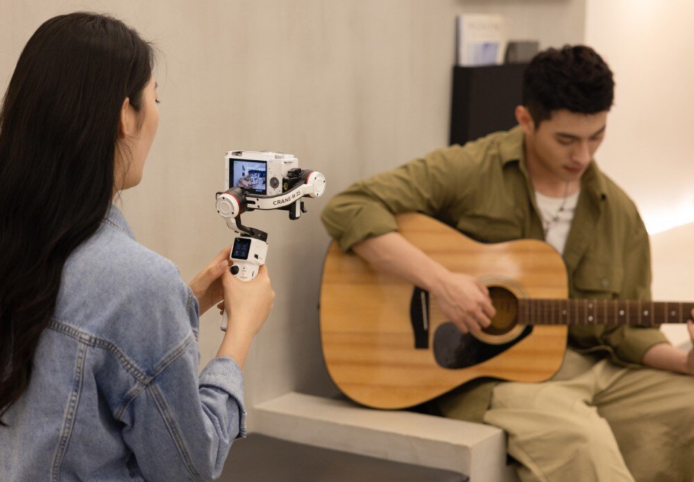 Gimbal ZHIYUN Crane M3S kobieta trzymająca gimbal z aparatem, nagrywająca mężczyznę grającego na gitarze stabilizacja waga udźwig