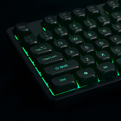 Czarna klawiatura z podświetleniem w kolorze zielonym, widoczne klawisze to m.in. \'Shift\', \'Ctrl\', \'Caps Lock\'.