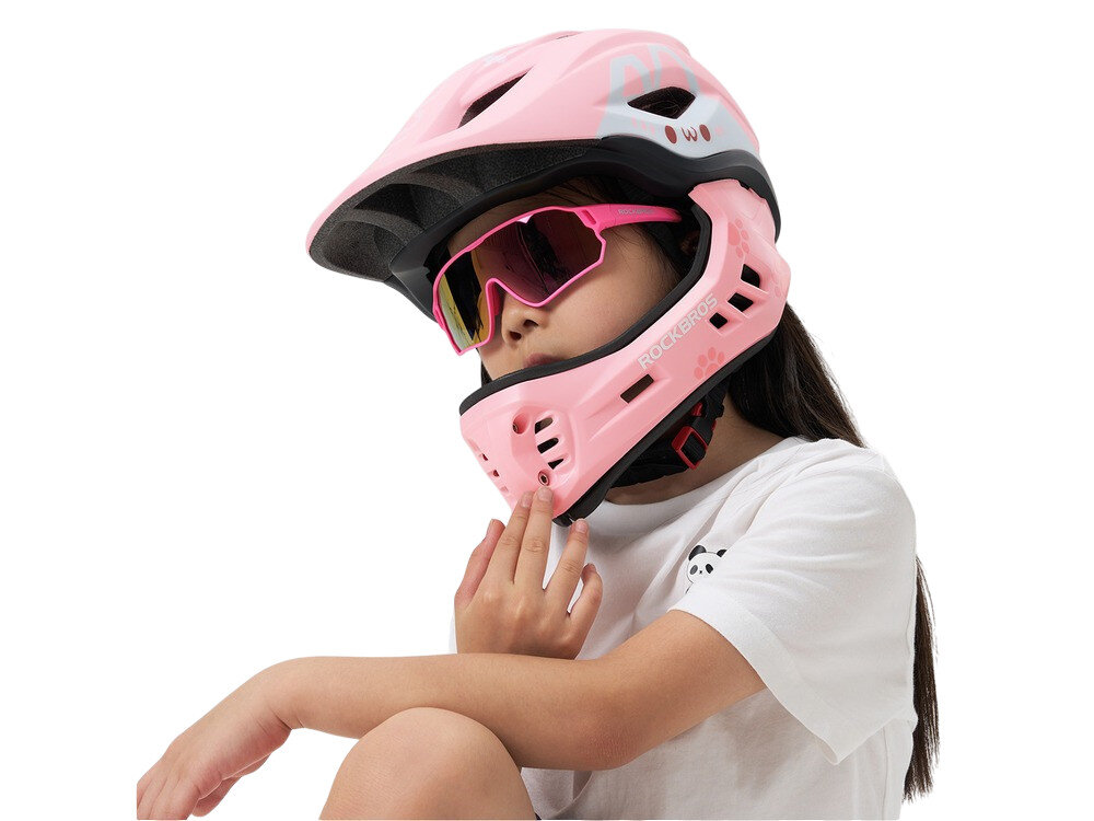Kask rowerowy ROCKBROS TT-32002 Rabbit Różowy Full Face dla Dzieci z odkręcaną szczęką (rozmiar M), kask, dziecko, rower, bezpieczeństwo, Dziewczynka w kasku ochronnym trzyma dłoń przy brodzie.