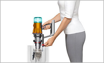 Zdjęcie pokazuje osobę wyrzucającą zanieczyszczenia z pojemnika odkurzacza do kosza na śmieci