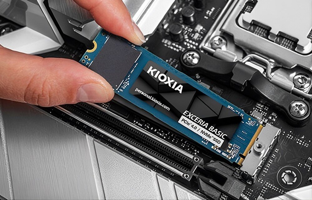 Dysk KIOXIA Exceria Basic Ludzkie palce wsuwające wewnętrzny dysk SSD M.2 do gniazda na płycie głównej komputera, obok innych podzespołów elektronicznych, technologia, wydajność, szybkość