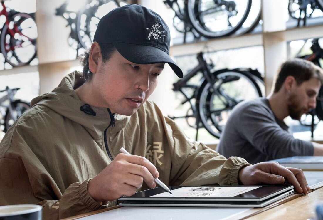 Osoba pracująca na laptopie HP OmniBook w trybie tabletu w sklepie rowerowym, korzystająca z rysika.