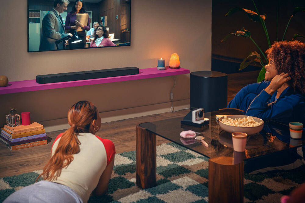 Soundbar JBL BAR 500 MkII technologia Dolby Atmos dźwięk 3D kino domowe, soubndbar stojący na blacie, subwoofer stojący na ziemi, osoby oglądające film na telewizorze