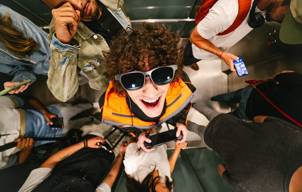 Okulary VITURE XR Luma Pro Large okulary założone na chłopaku zdjęcie zrobione z góry wokół tłum ludzi rozdzielczość jasność szerokie pole widzenia system audio klasy premium rozrywka praca