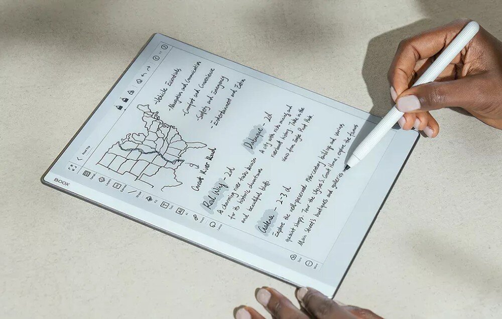 Czytnik e-booków ONYX BOOX Go Osoba trzymająca elektroniczne urządzenie na stole, wykonująca notatki i szkice na mapie za pomocą rysika, kompatybilność, formaty, pamięć, pojemność