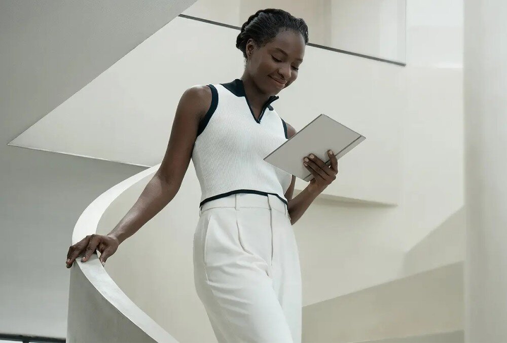 Czytnik e-booków ONYX BOOX Go Kobieta w eleganckim stroju, idąca po schodach i trzymająca czytnik e-booków w jednej ręce, wygląd, materiał, kolor