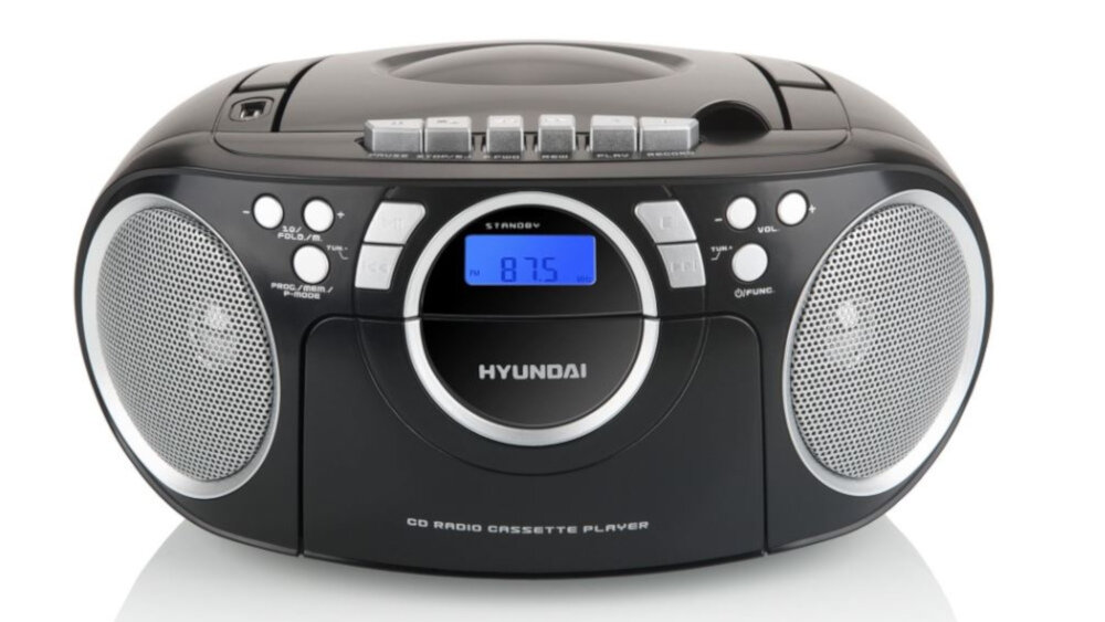 Czarno-niebieski radioodtwarzacz z widocznym logo Hyundai, posiada dwa głośniki i wyświetlacz LCD pokazujący częstotliwość 87.5. Na górze znajdują się przyciski sterujące oraz miejsce na płyty CD.