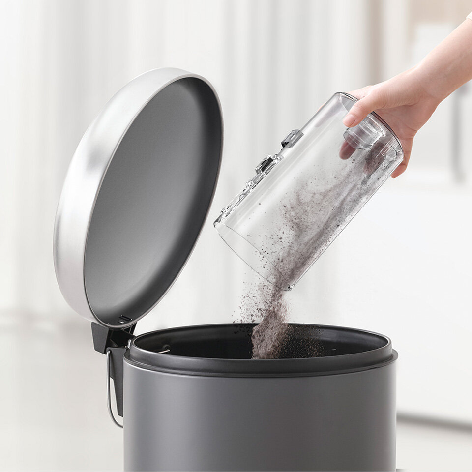 zdjęcie pokazuje wysypywanie zanieczyszczeń z pojemnika odkurzacza do kosza na śmieci