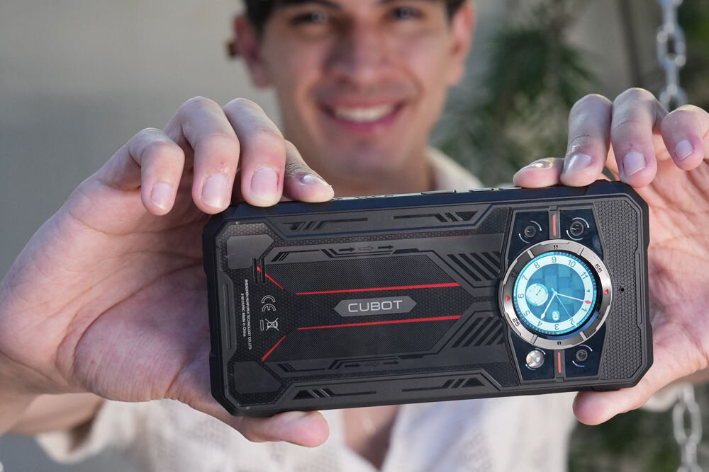 Smartfon CUBOT King Kong 11 5G 16/256GB 6.72 120Hz Czarny Uśmiechnięty mężczyzna trzyma oburącz pancerny smartfon Cubot, prezentując jego tył z okrągłym wyświetlaczem pomocniczym