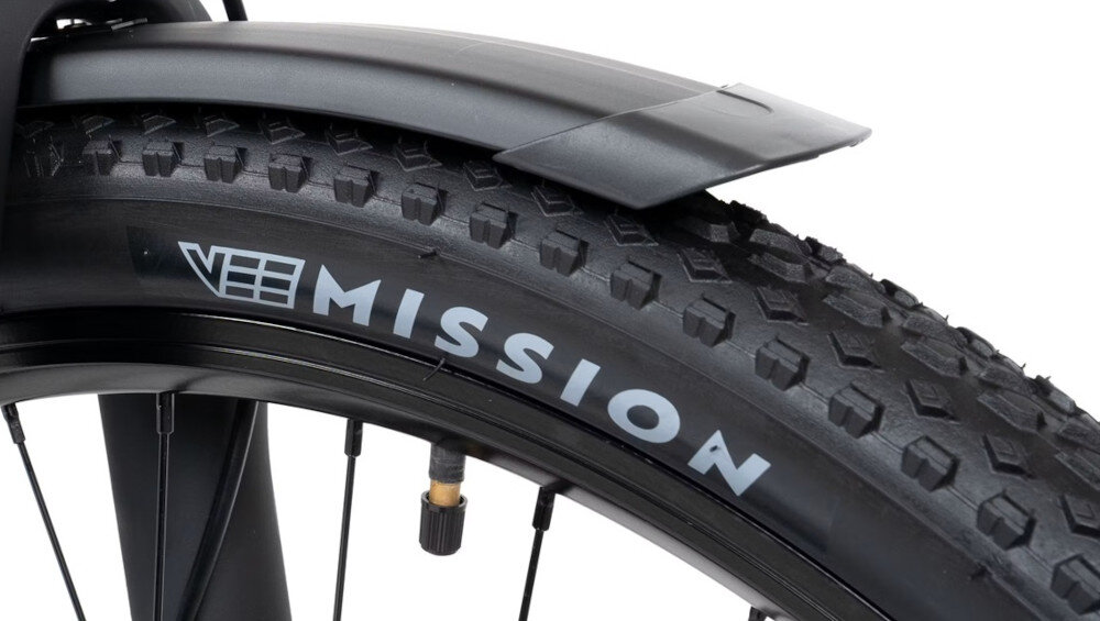 Zbliżenie na oponę rowerową z widocznym bieżnikiem i napisem \'MISSION\'.