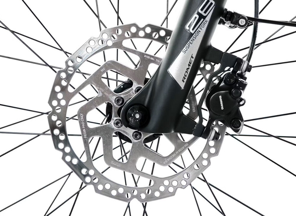 Zbliżenie na tarczę hamulcową roweru z widocznym napisem \'ROMET\' na widelcu oraz \'SHIMANO\' na zacisku hamulcowym.