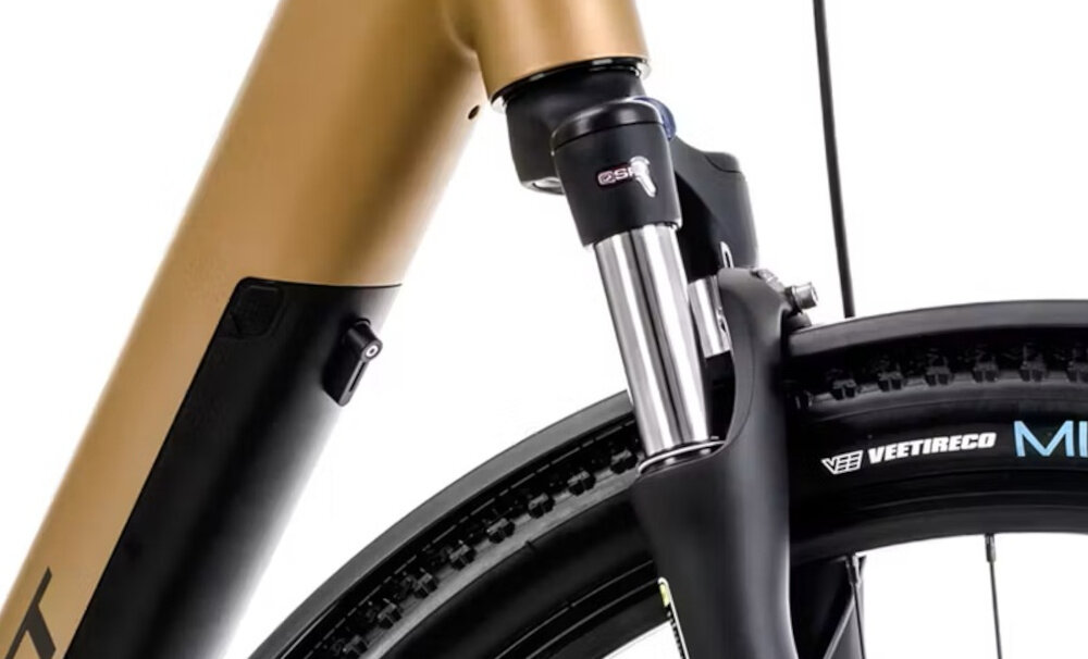 Rower elektryczny ROMET E-Modeco SUV 1.0 AN D U17 28 cali Złoty zbliżenie na amortyzator widok z boku przedni amortyzator Suntour NEX E25 o skoku 75 mm tłumi nierówności konstrukcja tapered poprawia sztywność oraz precyzję prowadzenia budowa typu hardtail energia pedałowania nie jest tracona na tylne zawieszenie zwiększa efektywność jazdy
