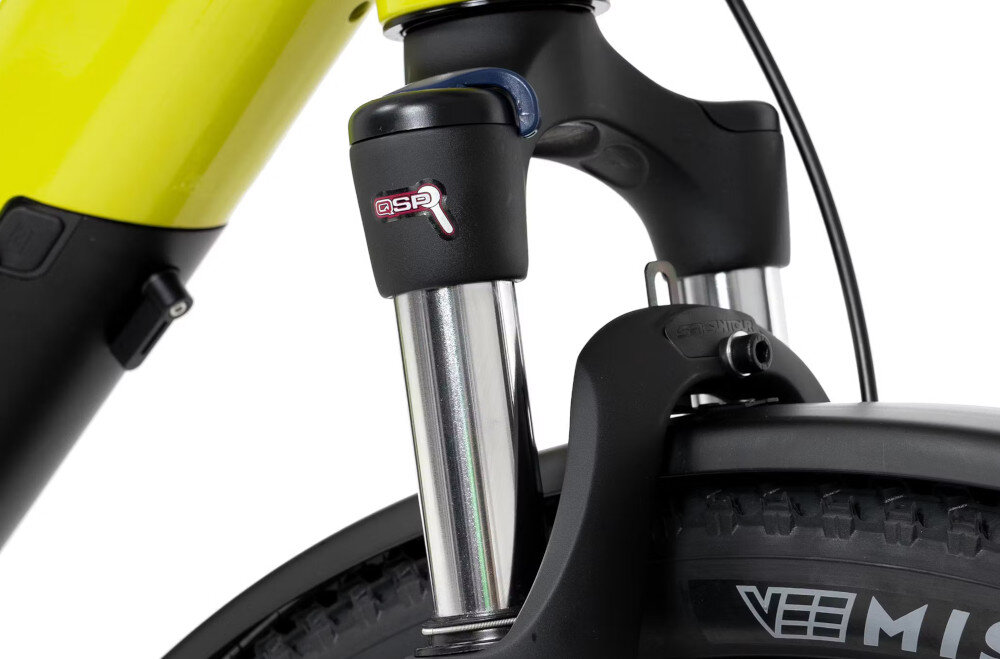 Zbliżenie na przedni amortyzator roweru z widocznym logo \'QSP\' na czarnym elemencie. Opona ma napis \'VEE M4\'.