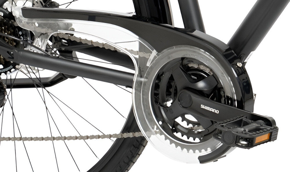 Zdjęcie przedstawia mechanizm napędowy roweru z widoczną osłoną łańcucha i pedałem. Na korbie widoczny jest napis \'SHIMANO\'.