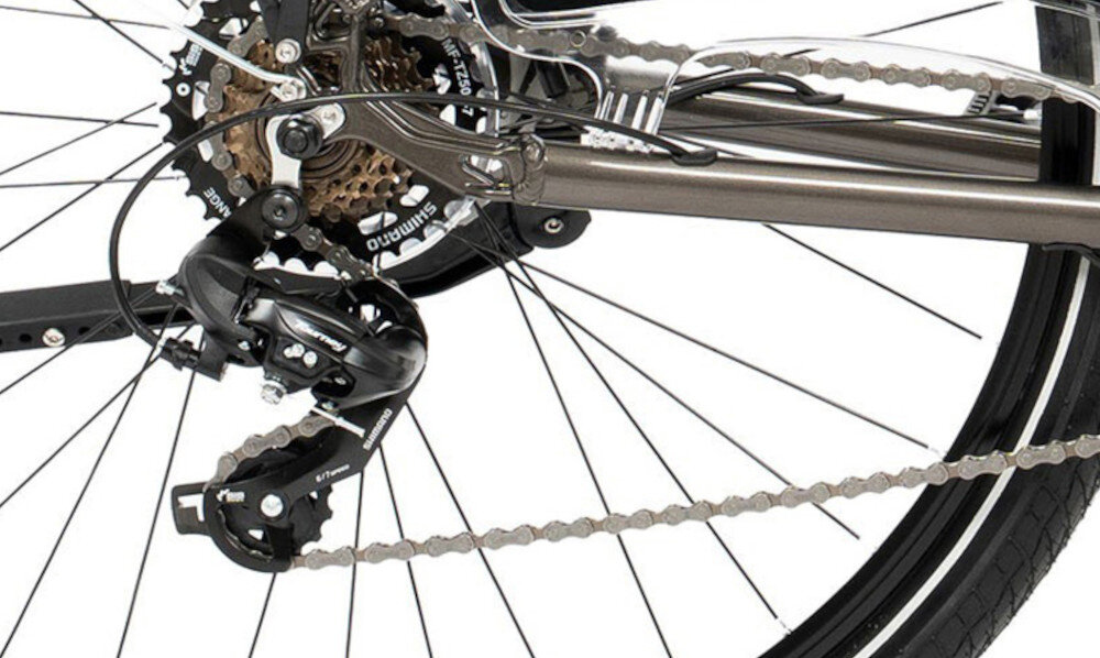 Zdjęcie przedstawia tylną część roweru z widocznym mechanizmem przerzutki i łańcuchem. Na przerzutce widoczny jest napis \'Shimano\'.