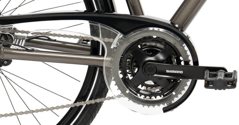 Zdjęcie przedstawia mechanizm napędowy roweru z widocznym łańcuchem, zębatkami i pedałem. Na ramieniu mechanizmu znajduje się napis \'SHIMANO\'.