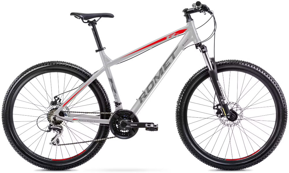Rower górski MTB ROMET Rambler R7.1 U17 27.5 cala Srebrno-czerwono-grafitowy rower na białym tle widoczny z boku góral pojazd dla sportowców do jazdy wyczynowej uniwersalny dla amatorów zwrotny łatwo wchodzi w zakręty do jazdy w mieście za miastem w lesie na górskim szlaku w błocie nie za głębokim piachu