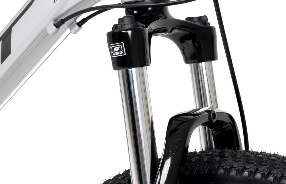 Rower górski MTB ROMET Rambler R7.1 U17 27.5 cala Srebrno-czerwono-grafitowy zbliżenie na amortyzator rower typu hardtail przedni amortyzator SUNTOUR typu XCE ze skokiem 100 mm ułatwia najeżdżanie na przeszkody niweluje wstrząsy niska masa roweru duża sztywność regulacja za pomocą sprężyny obsługa poprzez manetkę
