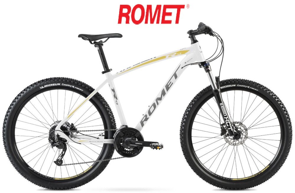 Rower górski MTB ROMET Rambler R7.3 U20 27.5 cala Biało-złoty rower na białym tle widoczny z boku na środku logo z napisem ROMET środek codziennego transportu relaks pasja uniwersalność