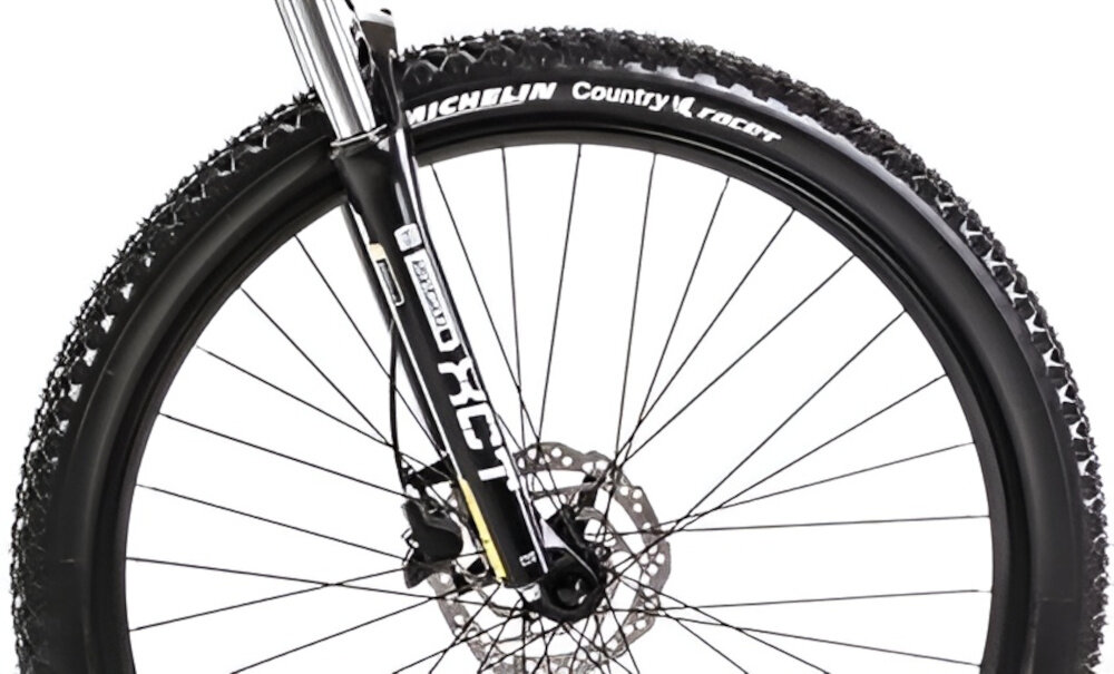 Zbliżenie na przednie koło roweru górskiego z widoczną oponą Michelin Country Racer i amortyzatorem z napisem RST. Koło posiada tarczę hamulcową.
