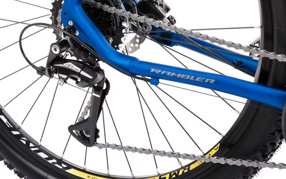 Rower górski MTB ROMET Rambler R7.3 C U20 27.5 cali Niebiesko-żółty zbliżenie na tylną przerzutkę przerzutki marki SHIMANO 3x8 przełożeń duża wytrzymałość i sprawne działanie zmiana biegów jest płynna i bezproblemowa przednia przerzutka SHIMANO Tourney tylna SHIMANO Acera komfort i kontrola