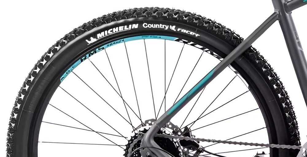 Rower górski MTB ROMET Rambler R7.4 A U20 27.5 cala Grafitowo-srebrno-turkusowy zbliżenie na tylną oponę widok z boku rozmiar koła 27,5 cali szybkie osiągnięcie docelowej prędkości jazdy łatwiej jest pokonać różne przeszkody szerokie opony marki MICHELIN z głębokim bieżnikiem dwukomorowe obręcze z aluminium zachowanie regularnego kształtu kół stabilne trzymanie opony bezpieczna i komfortowa jazda regularne sprawdzanie ciśnienia powietrza wartość na bocznej części opony