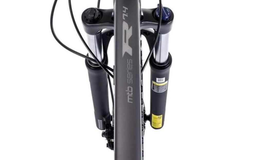 Rower górski MTB ROMET Rambler R7.4 C U18 27.5 cala Grafitowo-srebrno-turkusowy zbliżenie na amortyzator widok z góry rower typu hardtail przedni amortyzator SUNTOUR typu XCE HLO ze skokiem 100 mm ułatwia najeżdżanie na przeszkody niweluje wstrząsy niska masa roweru duża sztywność regulacja za pomocą sprężyny obsługa poprzez manetkę