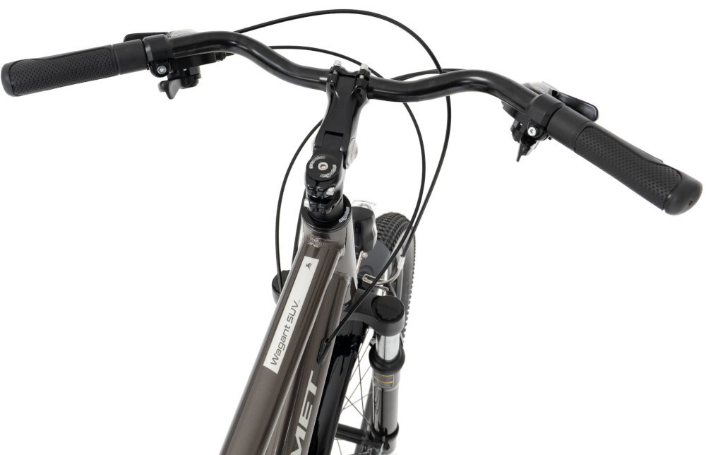 Zdjęcie przedstawia kierownicę roweru trekkingowego z widocznym napisem \'Wagant SUV\' na ramie. Rower ma grafitowy kolor i czarne uchwyty kierownicy.