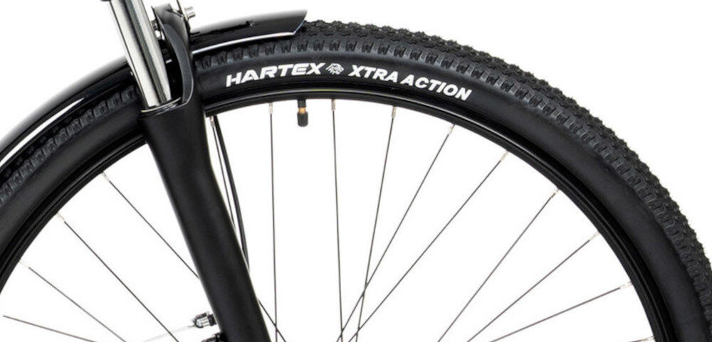 Zbliżenie na przednie koło roweru z widocznym napisem na oponie: \'HARTEX XTRA ACTION\'.