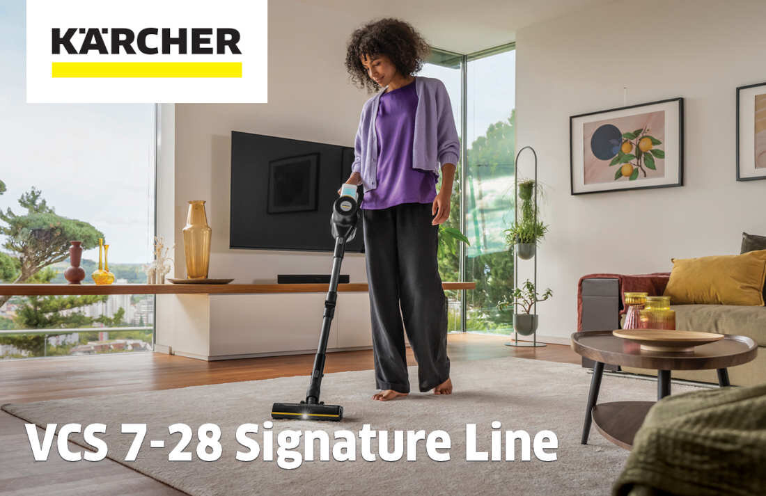 Osoba używa odkurzacza pionowego w nowoczesnym salonie. Widoczne jest logo \'KÄRCHER\' oraz tekst \'VCS 7-28 Signature Line\'.