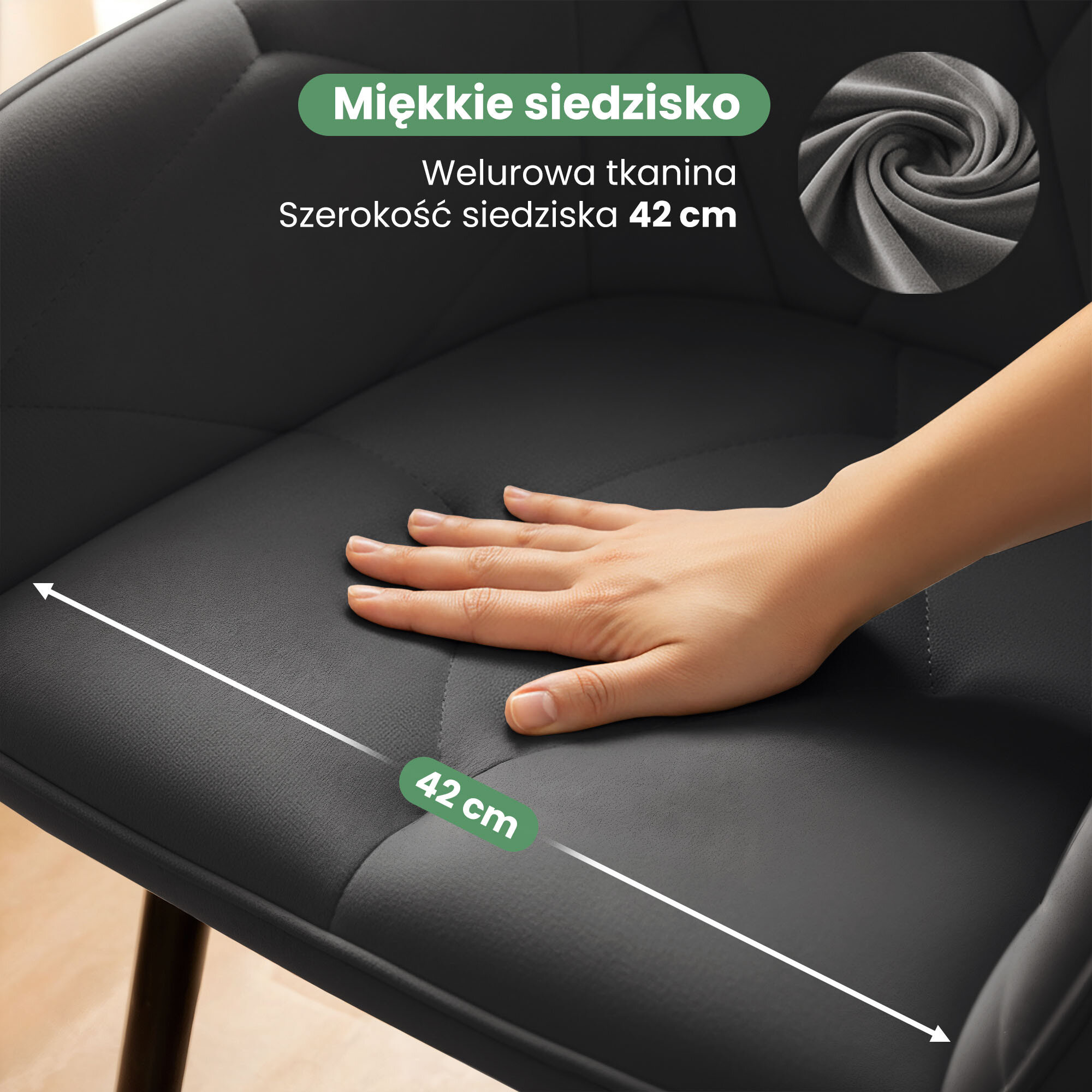 Na zdjęciu widać ciemnoszare, welurowe krzesło z pikowanym siedziskiem, na którym spoczywa dłoń. Tekst na obrazie: \'Miękkie siedzisko, Welurowa tkanina, Szerokość siedziska 42 cm\'.