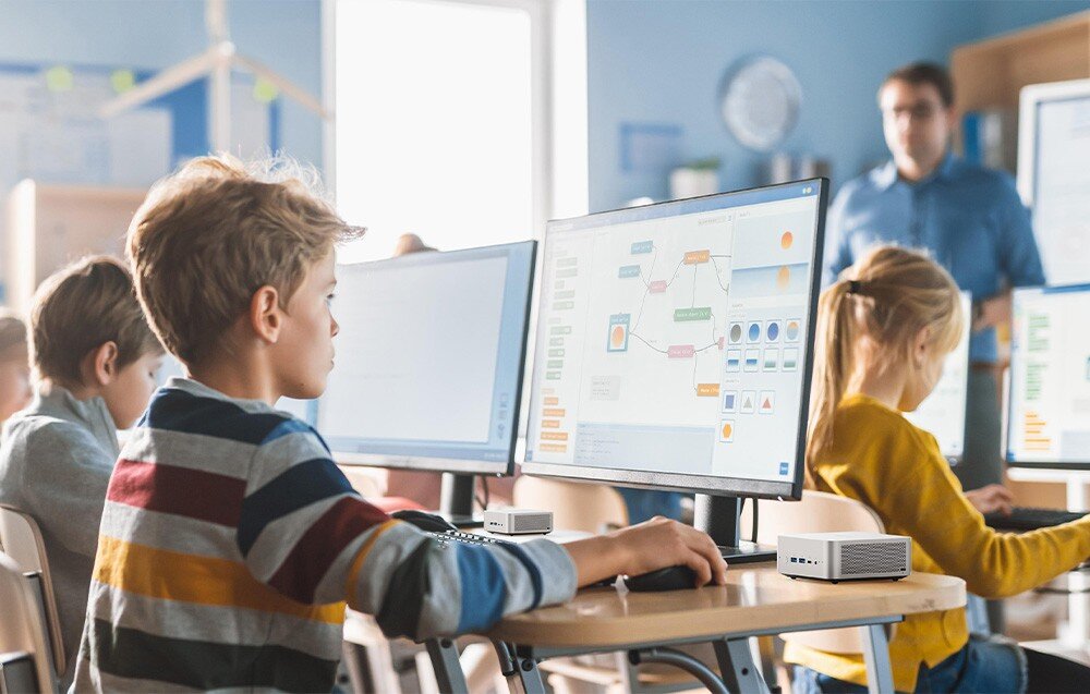 Komputer MINISFORUM X1-255 Dzieci pracują przy komputerach w klasie, a nauczyciel stoi w tle