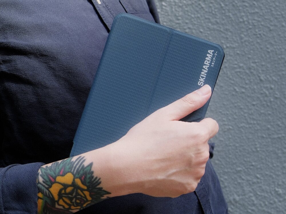 Etui na Kindle Paperwhite 12 SKINARMA Trax Niebieski, etui, skinarma, kindle, elegancja, etui trzymane jest w dłoni pod pachą osoby