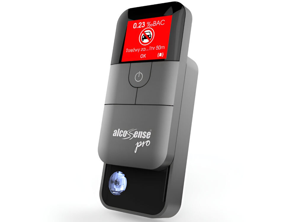 Na obrazie widoczny jest alkomat z wyświetlaczem pokazującym wynik 0.23 ‰BAC oraz komunikat \'Trzeźwy za... 1hr 50m\'. Na urządzeniu znajduje się logo \'alcoSense pro\'.