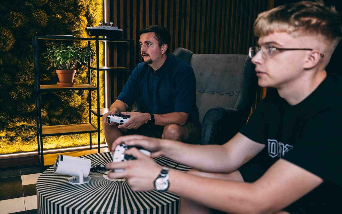 EXTRALINK GG300S kinie domowym, grach i edukacji dużym ekranem szybkie uruchamianie w około 3 sekundy - rzutnik na stoliku, dwóch mężczyzn trzymających pady