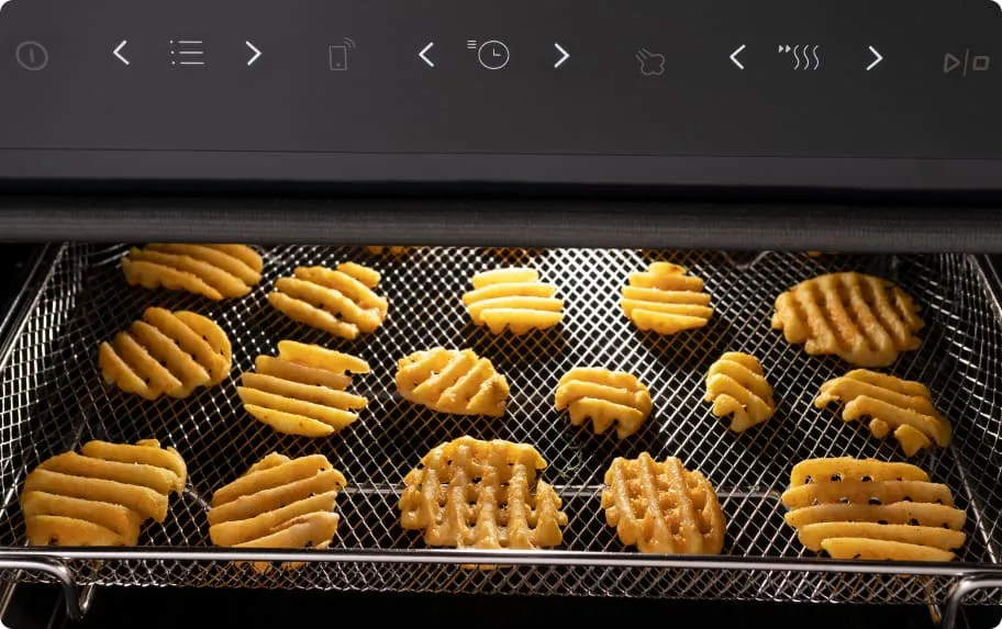 Wnętrze piekarnika z piekącymi się okrągłymi frytkami w kratkę