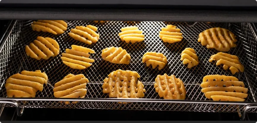 Wnętrze piekarnika z piekącymi się okrągłymi frytkami w kratkę