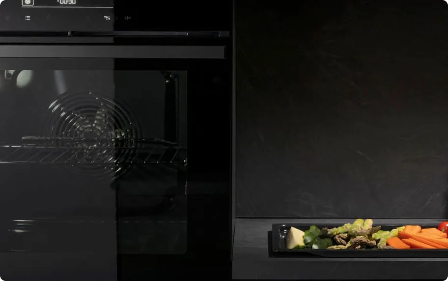 Piekarnik Hisense a obok blat kuchenny z blaszaną tacą pełną warzyw