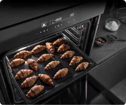 Na wpół wysunięta blacha piekarnika z rogalikami z czekoladą