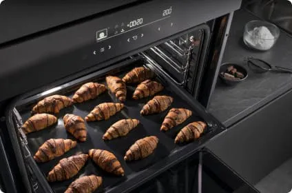 Na wpół wysunięta blacha piekarnika z rogalikami z czekoladą