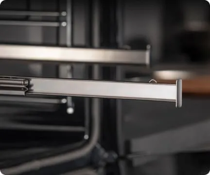 Zbliżenie na metalowe prowadnice teleskopowe w piekarniku Hisense