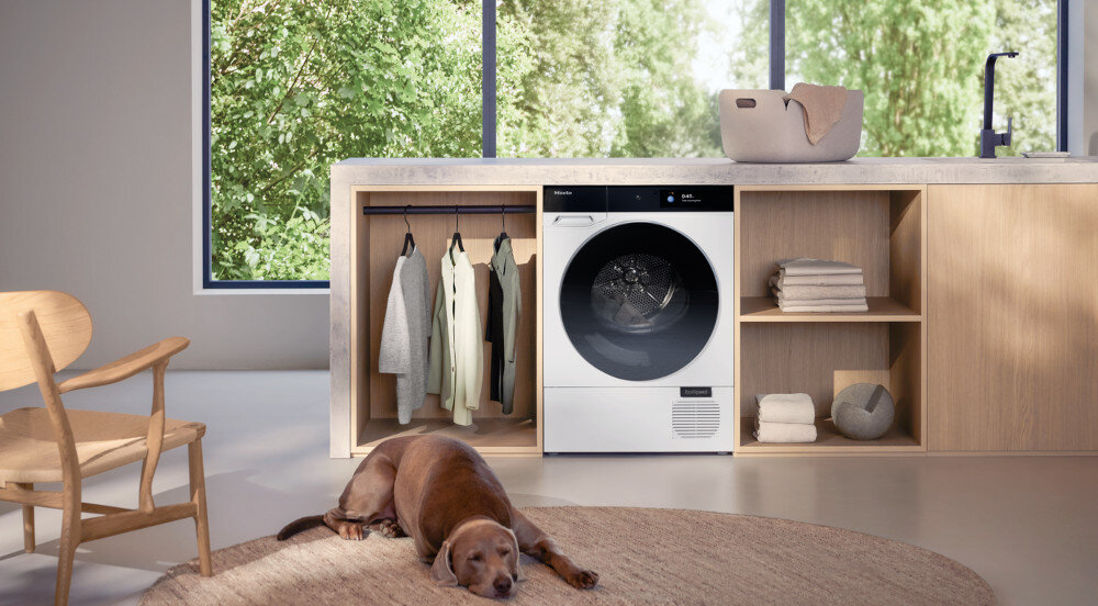 SUSZARKA MIELE TQ 1000 WP NOVA EDITION zdjęcie lifestyle pralka zabudowa front ubrania pies krzesło kosz Ciche suszenie SilenceDrum specjalna konstrukcja redukcja hałasu o połowę paski tłumiące